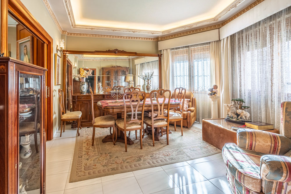 Formele eetkamer met klassiek houten meubilair, decoratieve plafondlijsten met indirecte verlichting en een groot spiegelbuffet dat de ruimte optisch vergroot.