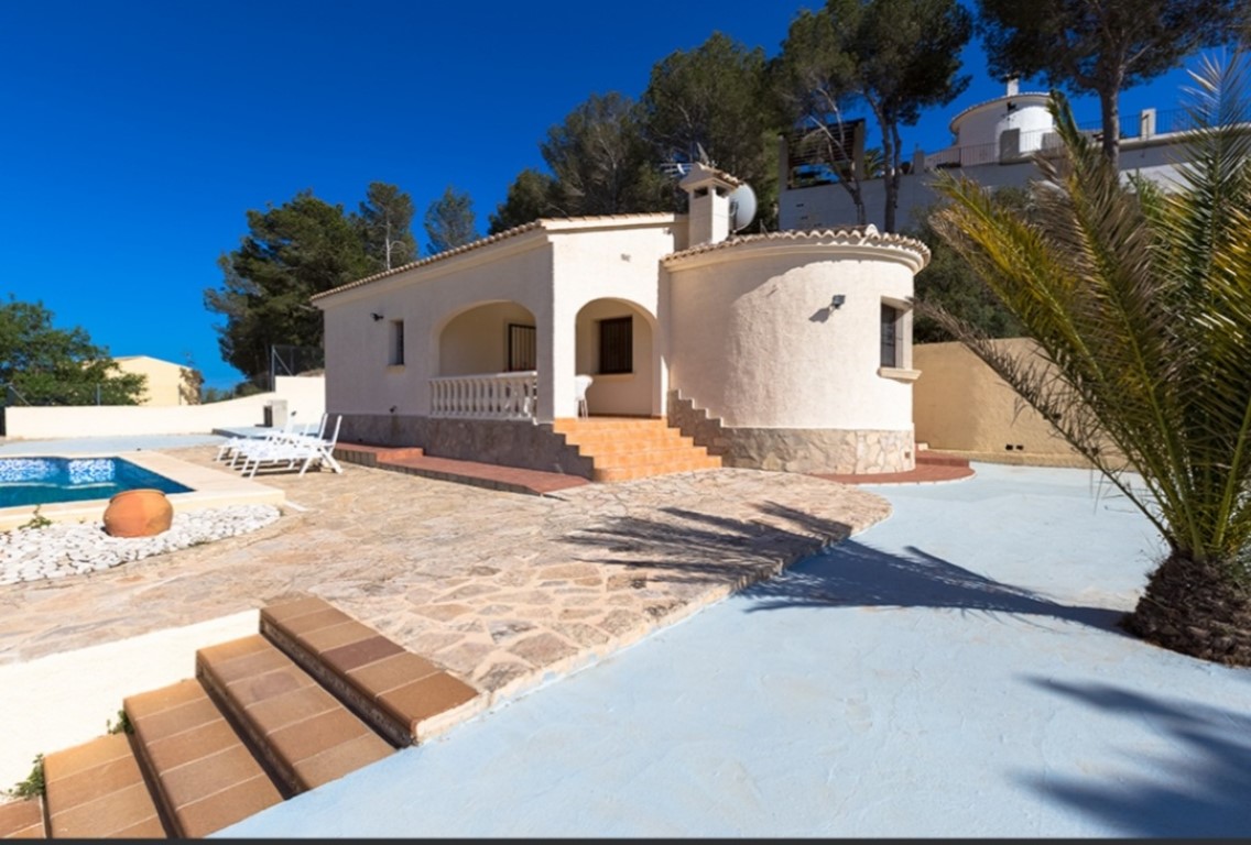 Exterieur van een traditionele villa met een overdekt terras met bogen, natuurstenen terras en privézwembad, omgeven door pijnbomen.