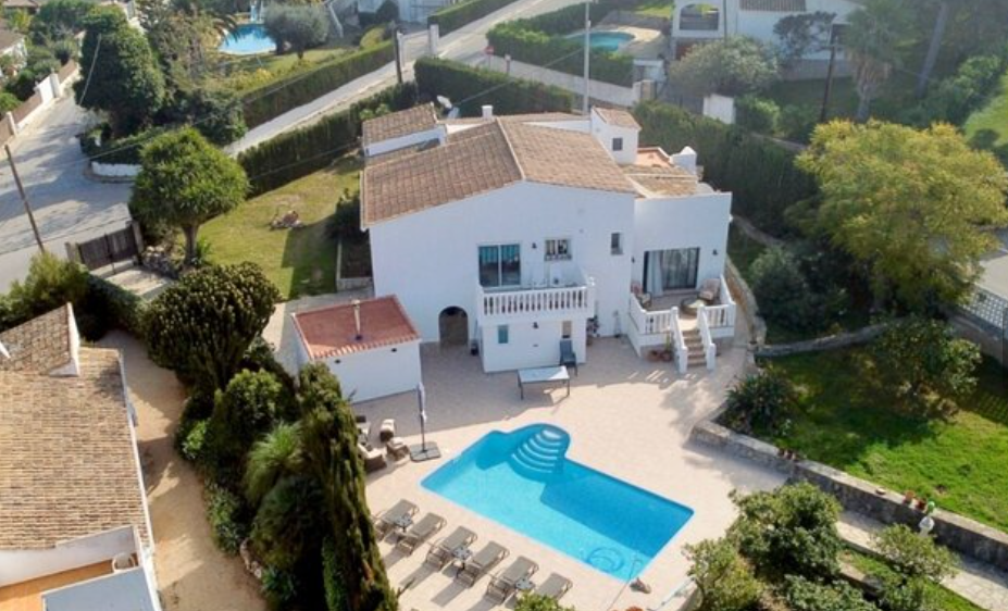 Luchtfoto van de villa met privézwembad, ruim zonneterras met ligstoelen en een volgroeide tuin rondom de traditionele witte gevel.