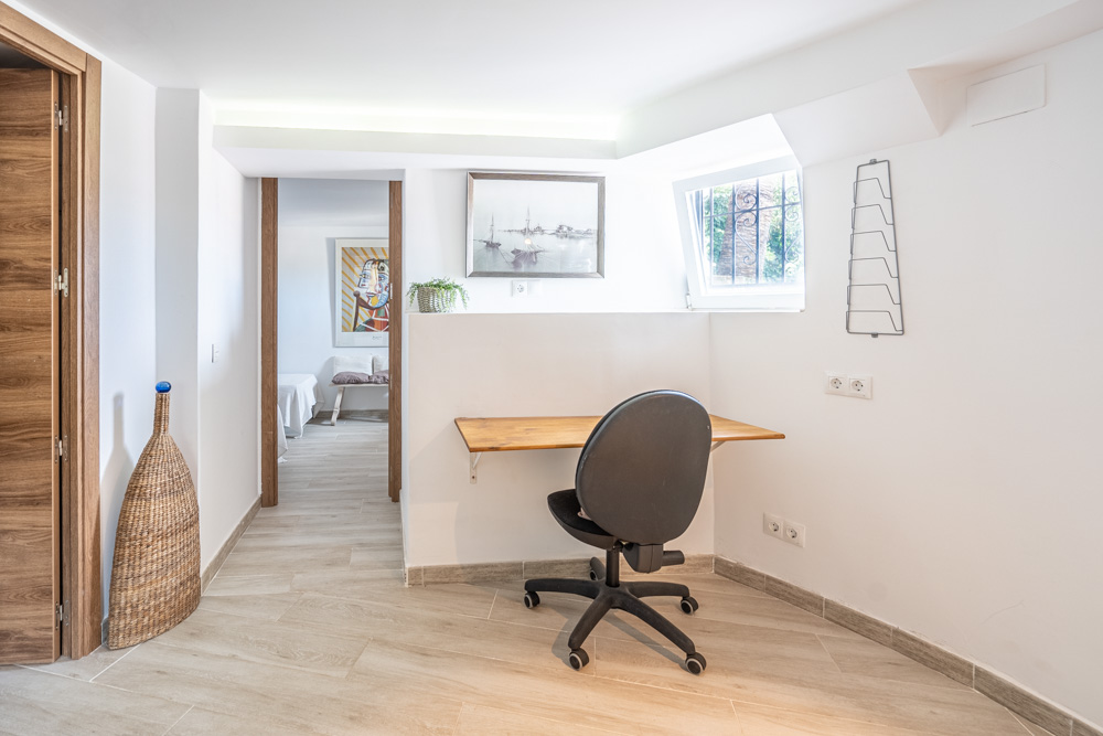 Geïntegreerde werkplek met houten bureau, ergonomische stoel en indirecte led-verlichting. Voorzien van keramische parketvloer en toegang tot de slaapkamers.