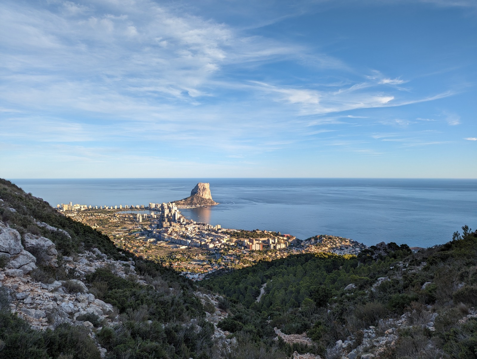 Panoramisch uitzicht op de Peñón de Ifach en de kustlijn van Calpe vanaf een hooggelegen punt, met de Middellandse Zee en het bergachtige landschap.