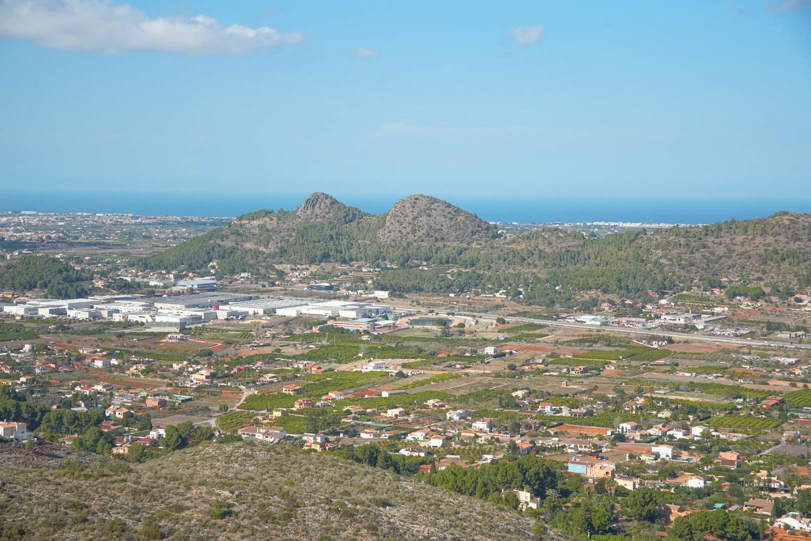 Panoramisch uitzicht over de vallei en de horizon van de Middellandse Zee, met de omliggende bergen en het kustlandschap van de Costa Blanca.