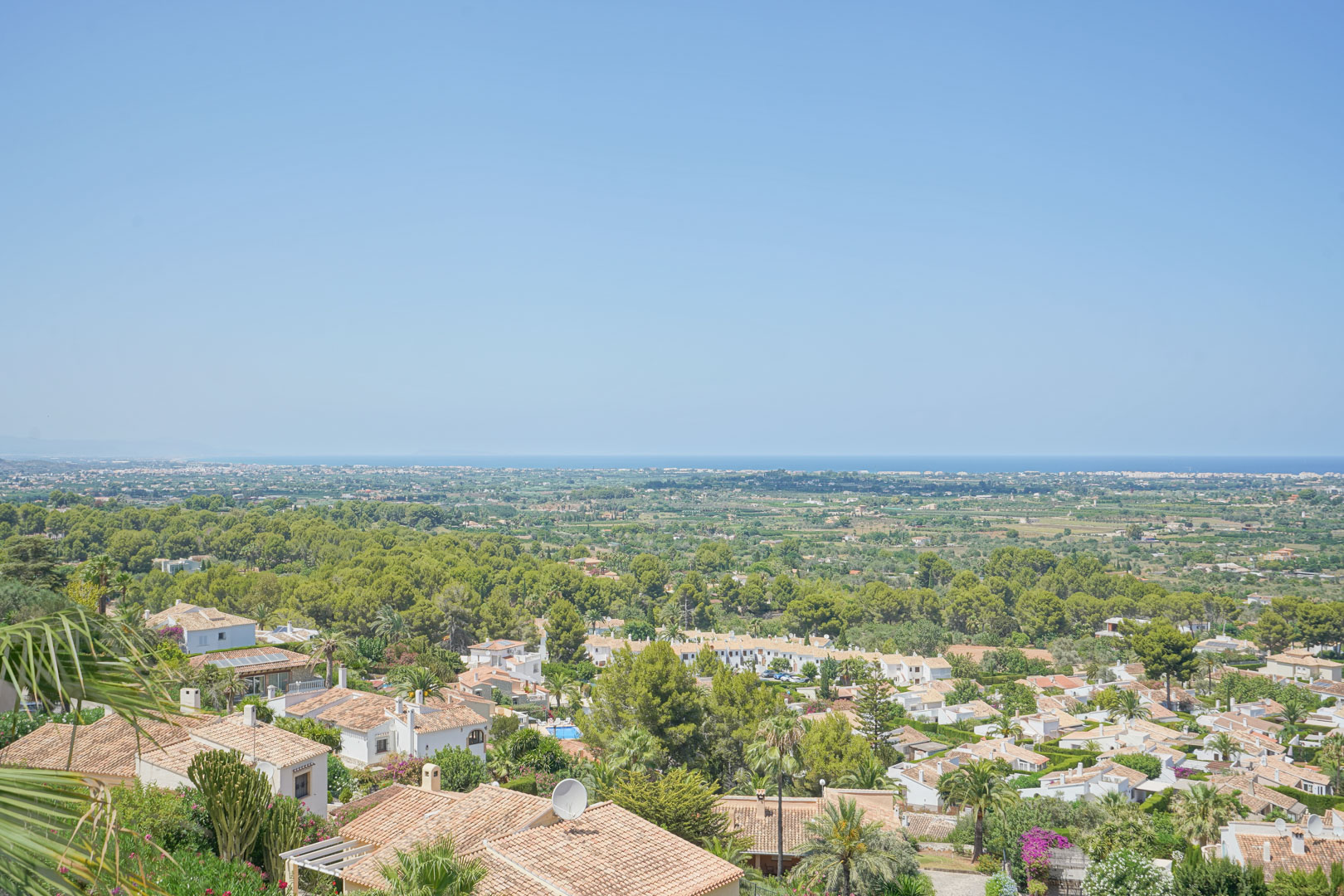 Panoramisch uitzicht vanaf het terras over de vallei en de Middellandse Zee, met weelderig groen en de karakteristieke terracotta daken van La Sella.