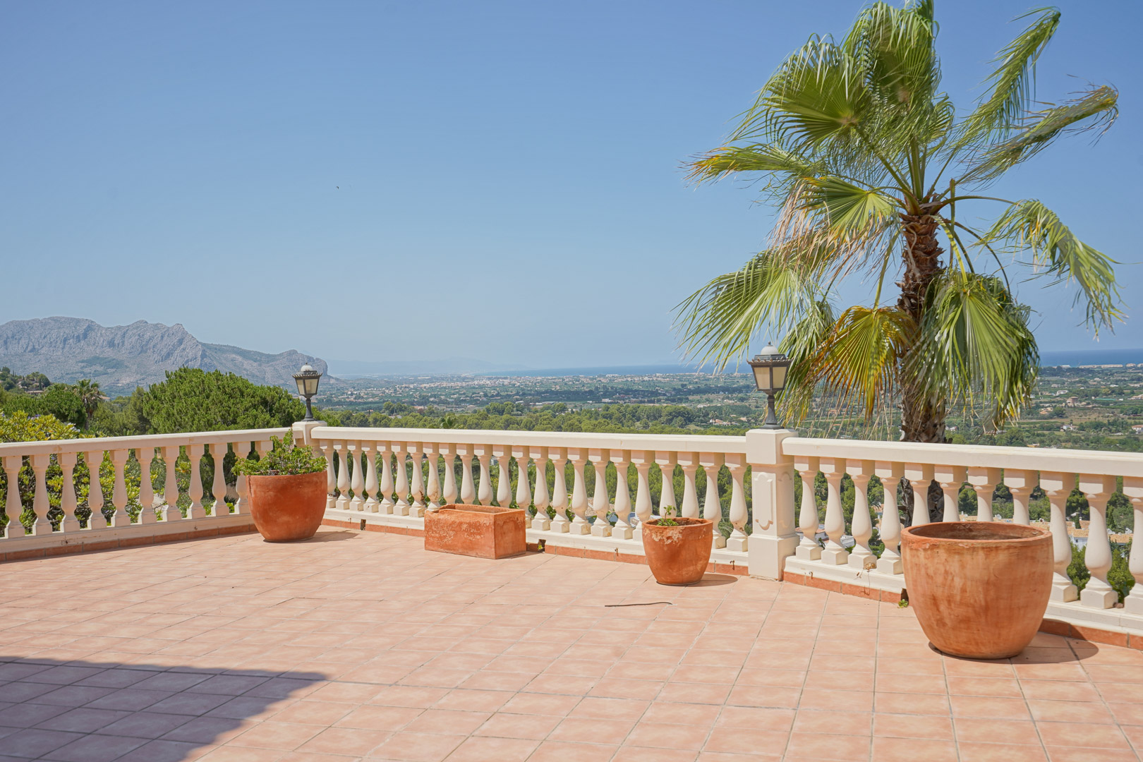Verhoogd terras met terracotta tegels en een klassieke witte balustrade, met panoramisch uitzicht over de vallei en de Middellandse Zee.