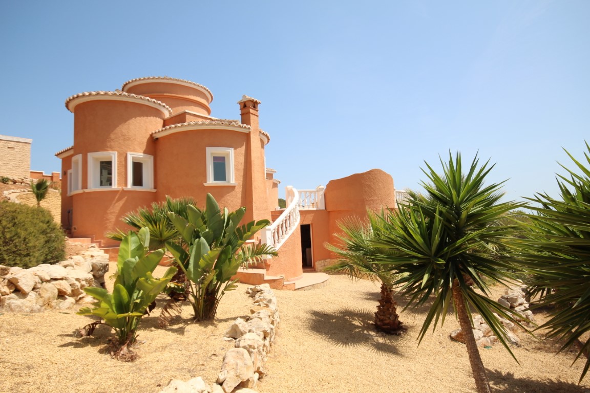 Mediterrane villa met terracotta muren, ronde vormen, een witte balustradetrap en een onderhoudsvriendelijke tuin met palmen en grind.