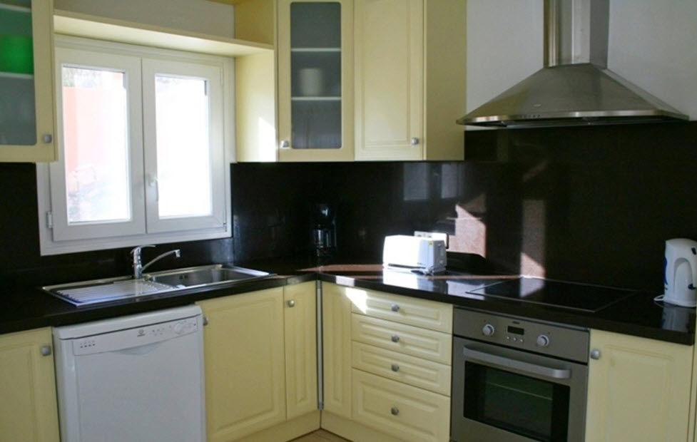 Volledig uitgeruste keuken met crèmekleurige kasten, een donker granieten werkblad en inbouwapparatuur. Voorzien van een keramische kookplaat, oven en dubbele spoelbak.