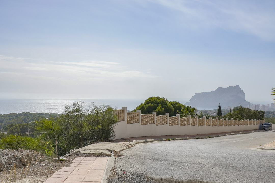Panoramisch uitzicht vanaf de toegangsweg, met de omheiningsmuur van het perceel en de Peñón de Ifach aan de horizon boven de Middellandse Zee.