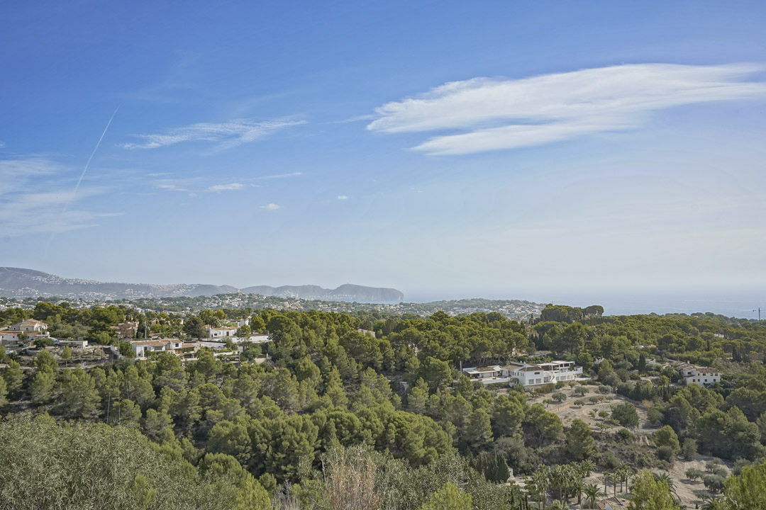 Panoramisch uitzicht vanaf de villa op de kustlijn van Moraira, met de Cap D'or en een uitgestrekt mediterraan landschap van pijnbomen.