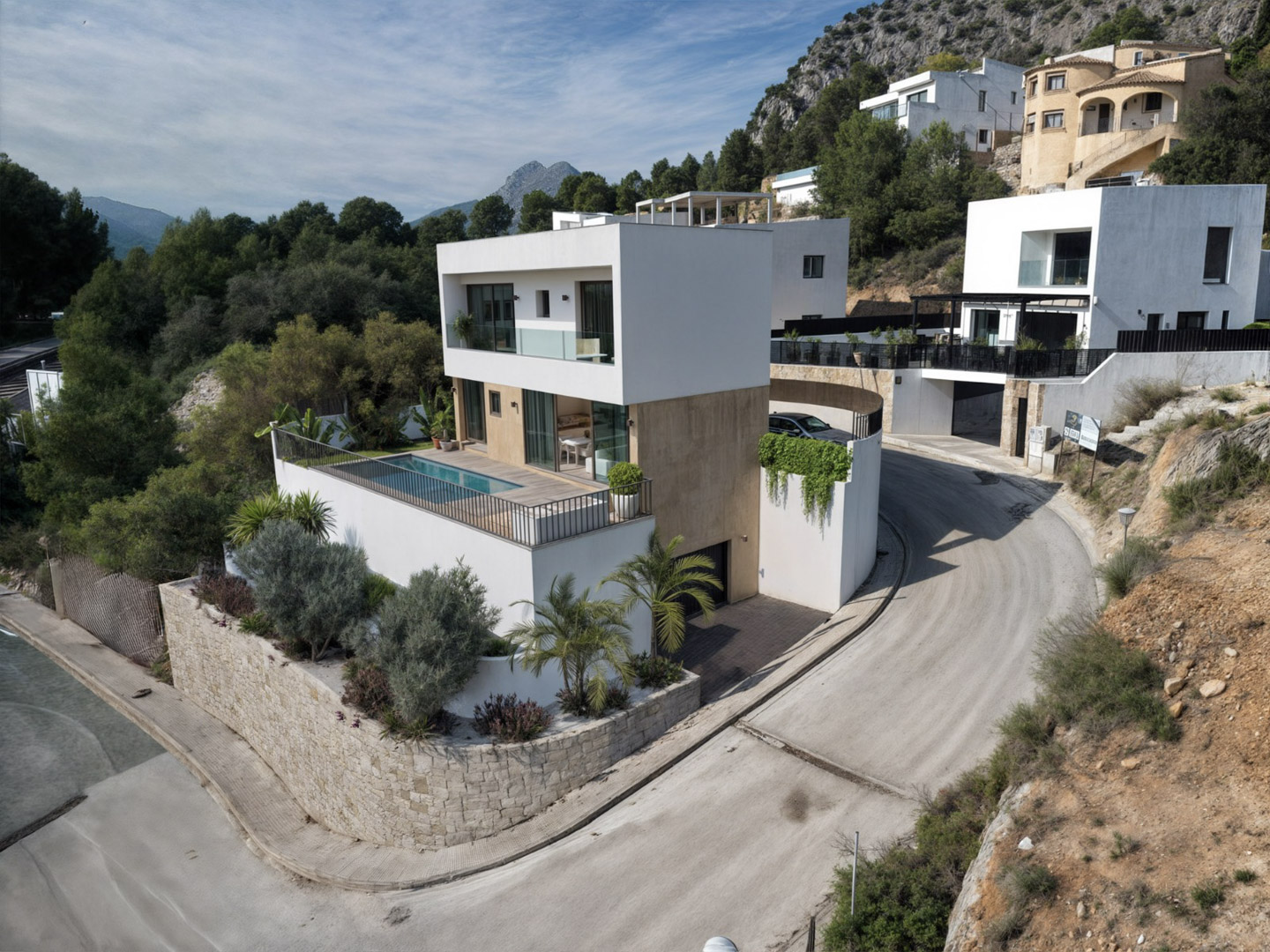 Exterieur van de moderne villa met witte gevel, stenen accenten, een terras met privézwembad en uitzicht op het berglandschap van Alcalalí.