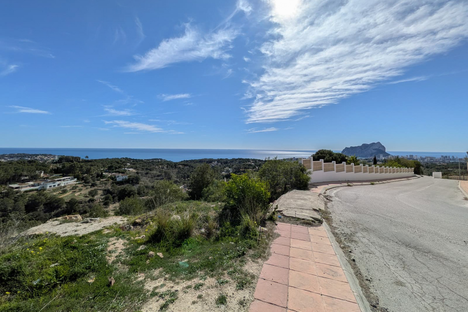 Panoramisch uitzicht vanaf de toegangsweg, met de kust van Benissa, de Middellandse Zee en het silhouet van de Peñón de Ifach aan de horizon.