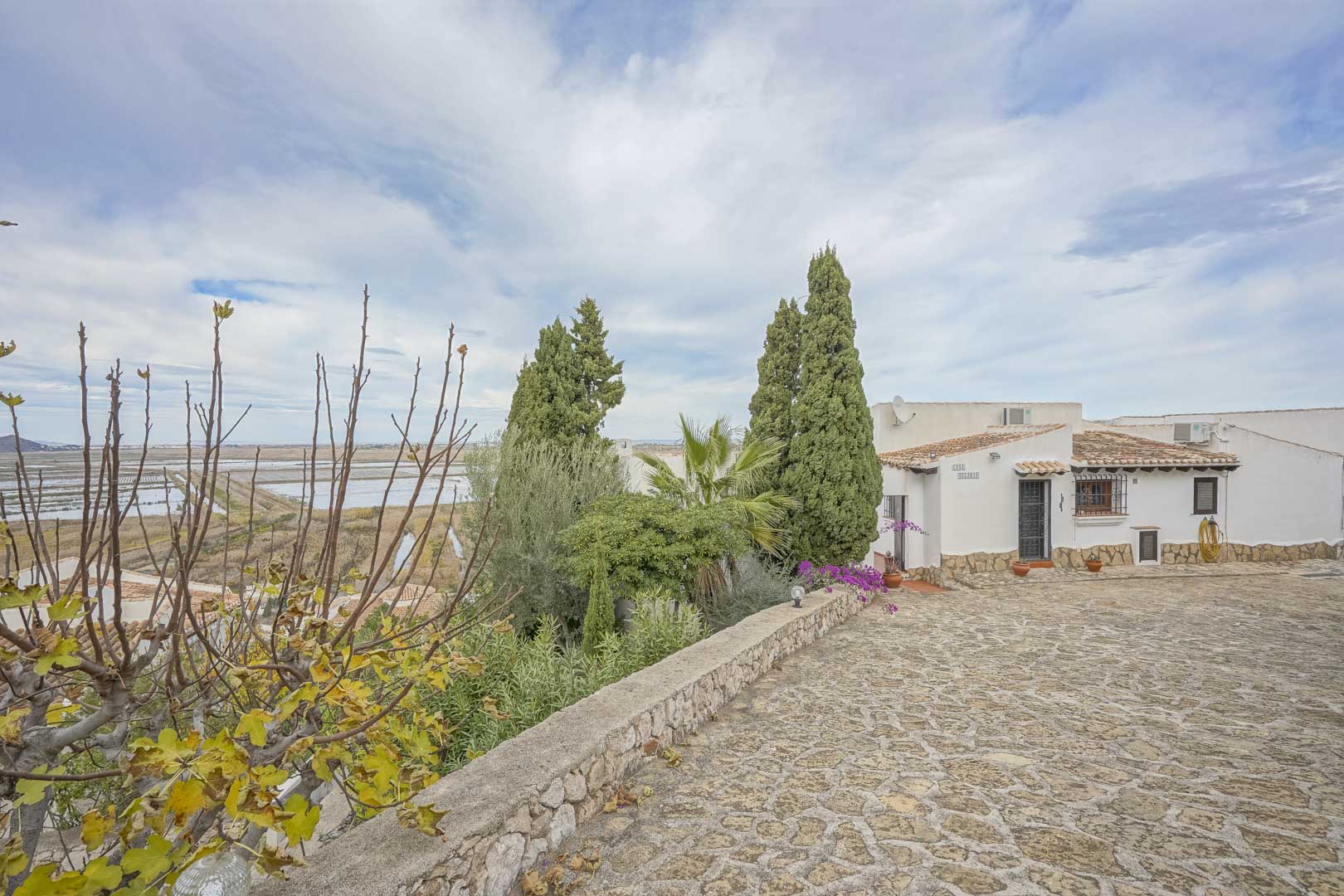 Buitenaanzicht van de villa met een stenen oprit, tuin en panoramisch uitzicht op het natuurreservaat.