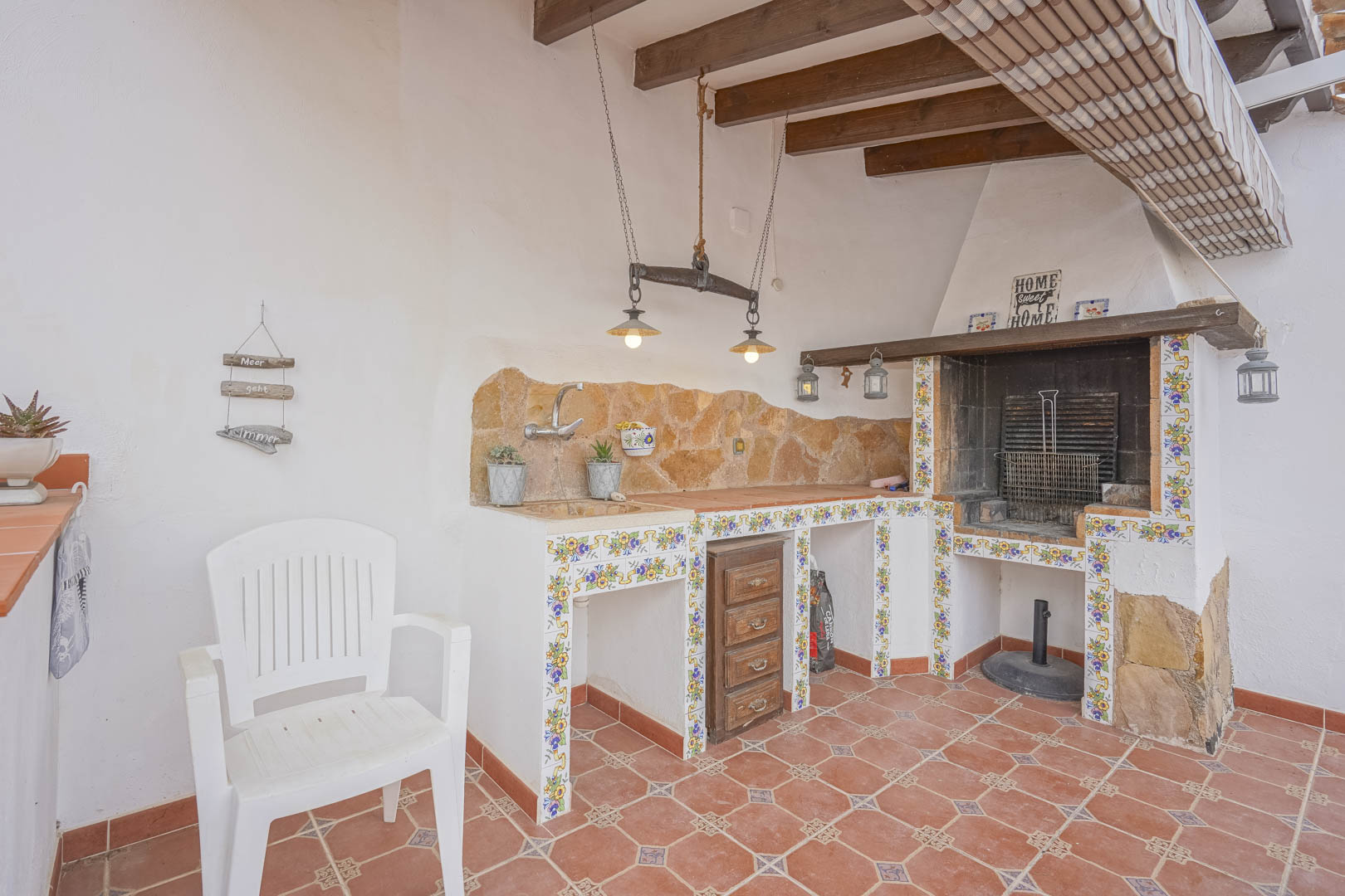 Buitenbarbecue met stenen aanrechtblad en decoratieve tegels in een villa in Spaanse stijl.