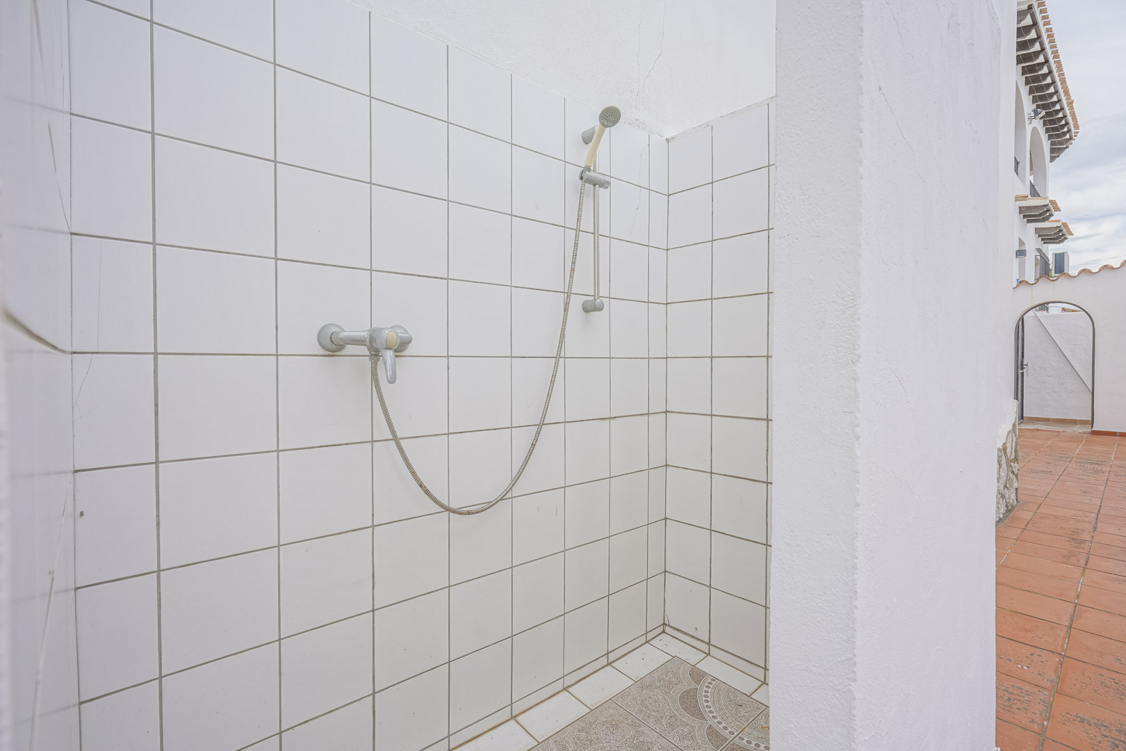 Buitendouche met witte tegels en decoratieve vloer in villa in Monte Pego.