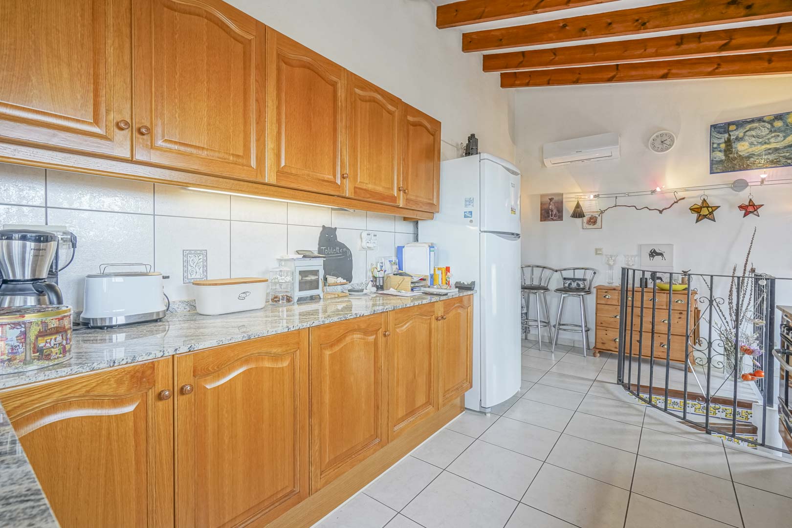 Gerenoveerde open keuken met houten kasten, granieten aanrechtbladen en moderne apparatuur.