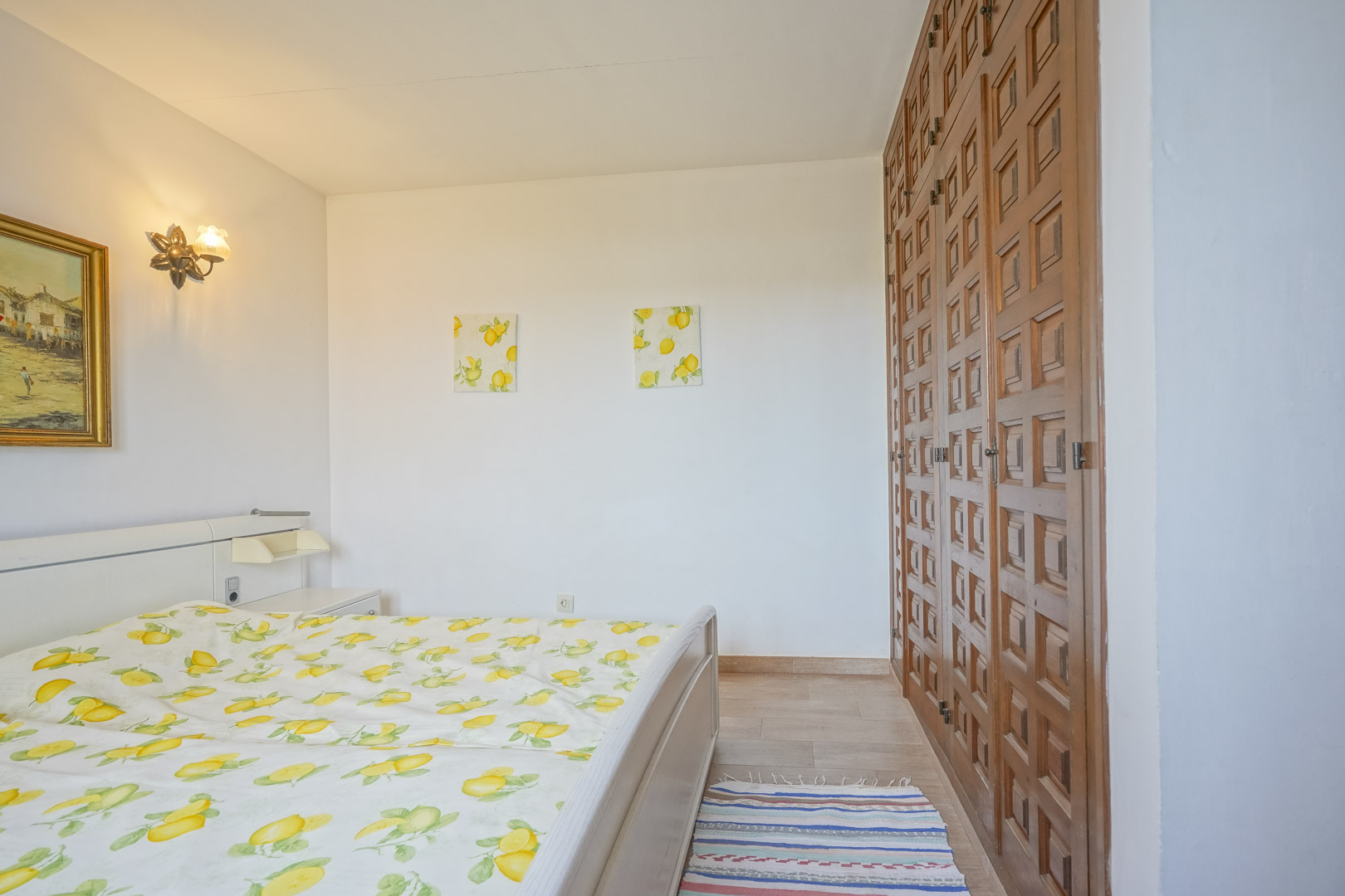 Lichte slaapkamer met bed, houten kledingkast en decor met citroenthema.