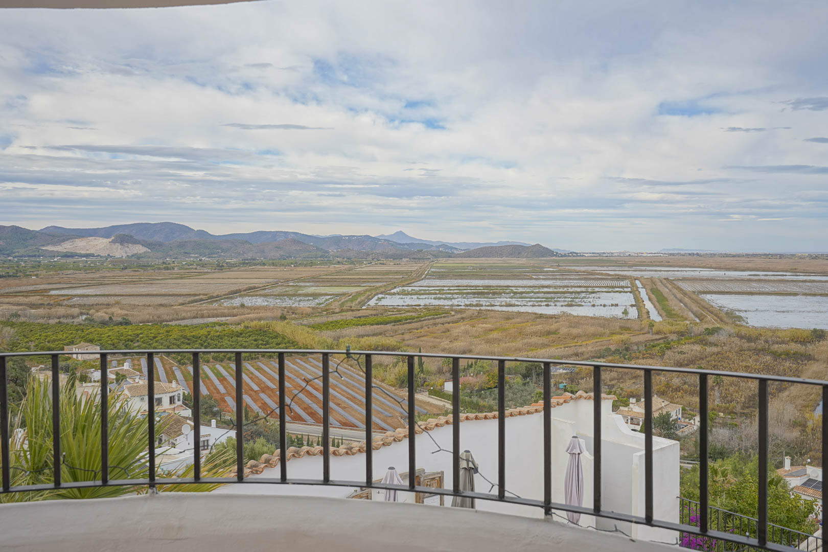 Panoramisch uitzicht vanaf het terras met smeedijzeren balustrade over de rijstvelden en het berglandschap.