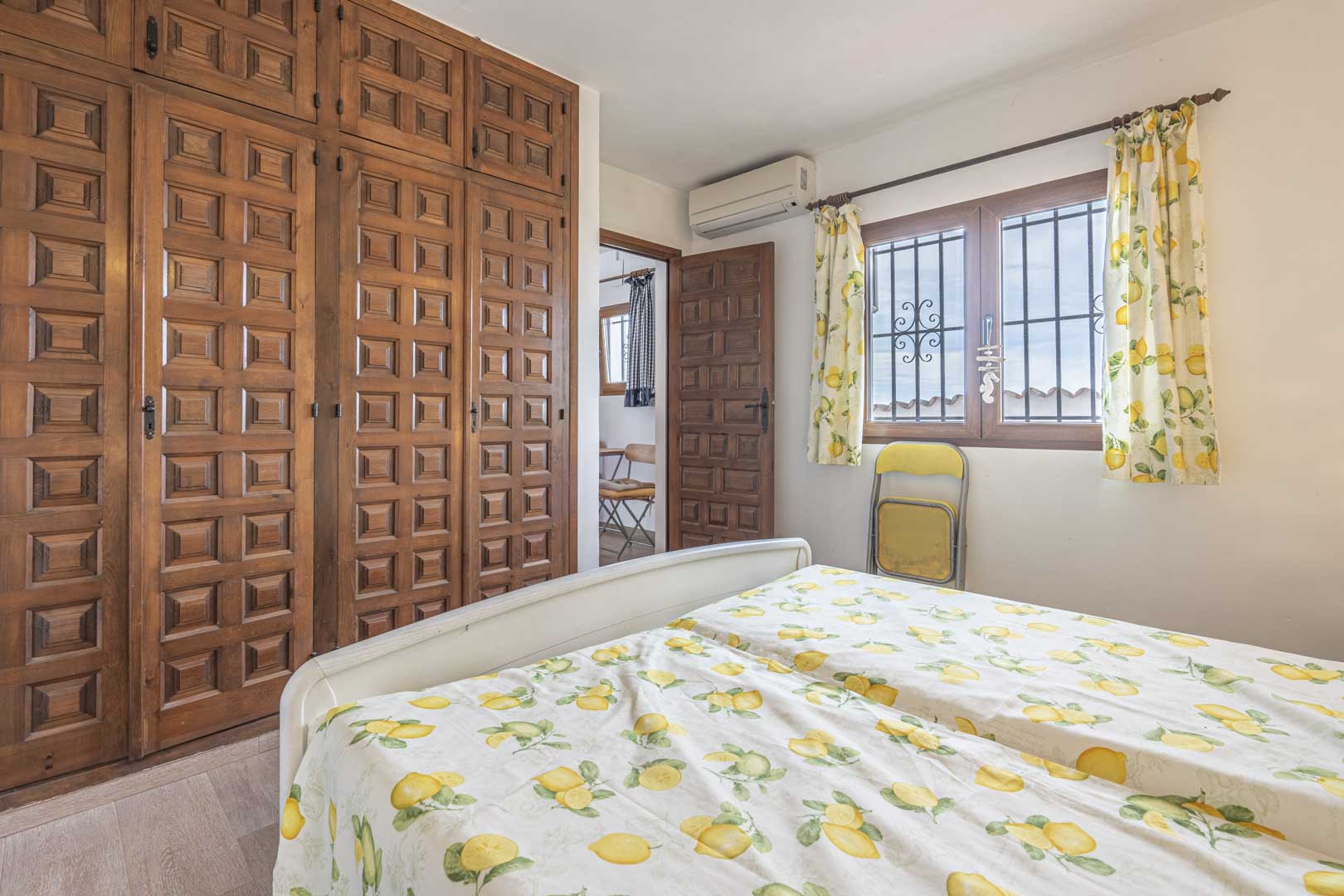 Slaapkamer met gesneden houten kledingkast en beddengoed met citroenprint.
