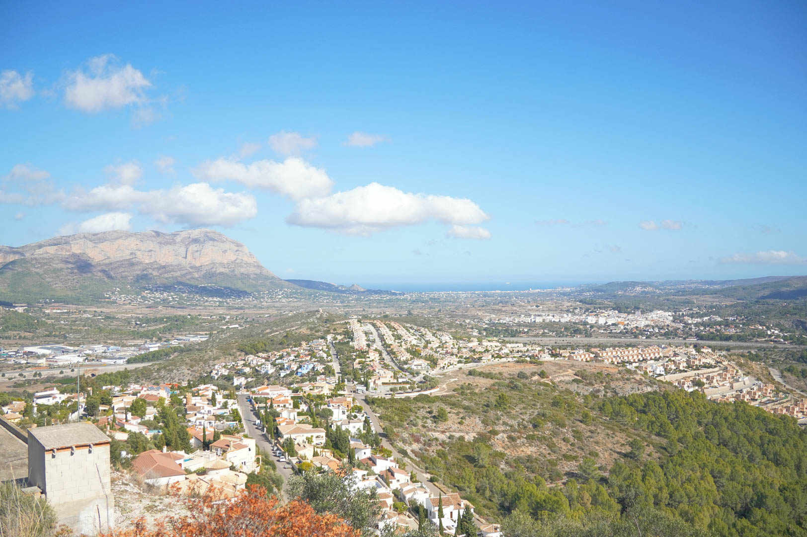 Panoramisch uitzicht over de vallei van Pedreguer en het Montgó-massief, met de Middellandse Zee zichtbaar aan de horizon onder een heldere hemel.