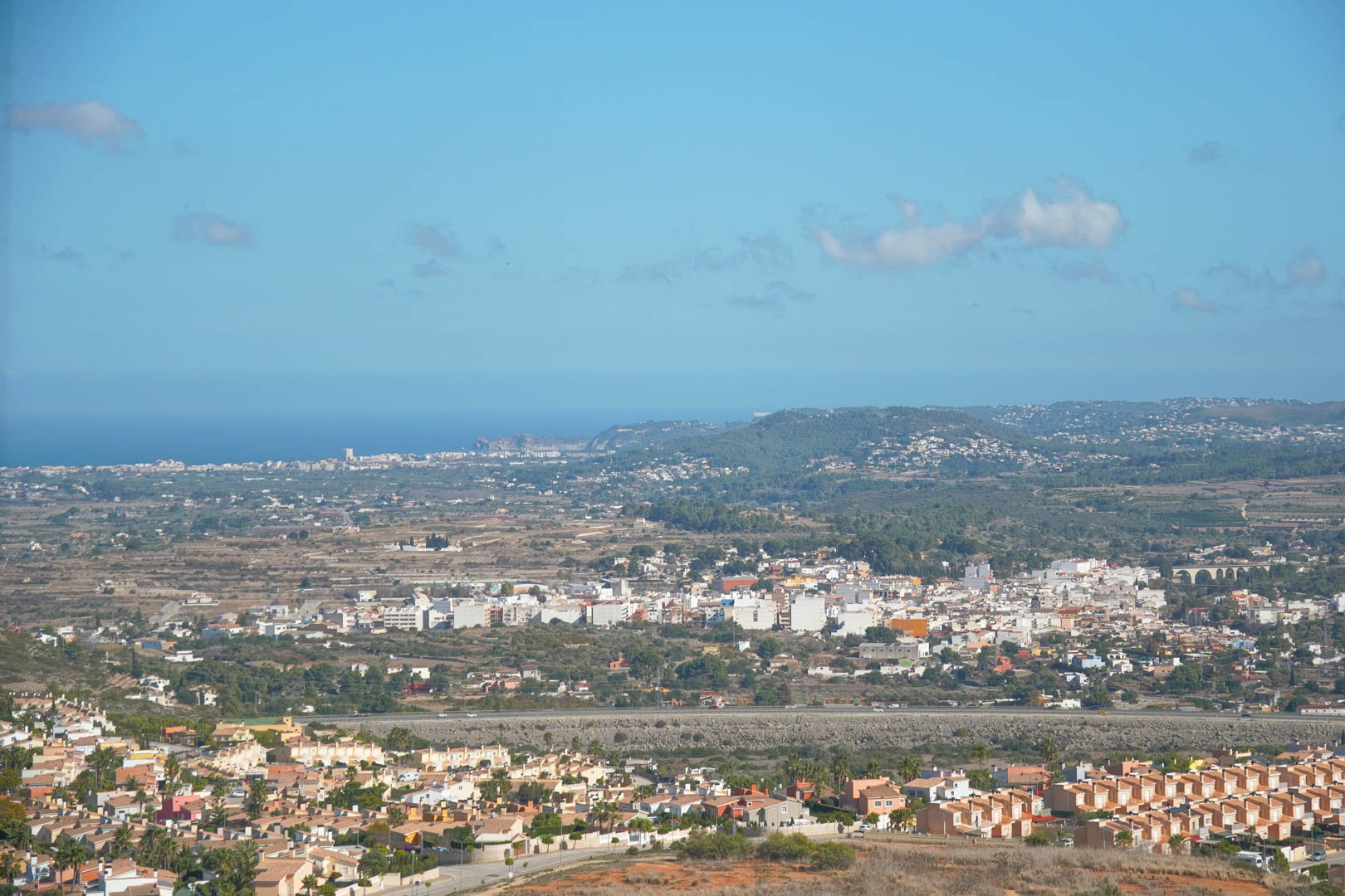 Panoramisch uitzicht vanaf het landgoed over de Pedreguer-vallei en de Middellandse Zeekust onder een helderblauwe hemel.