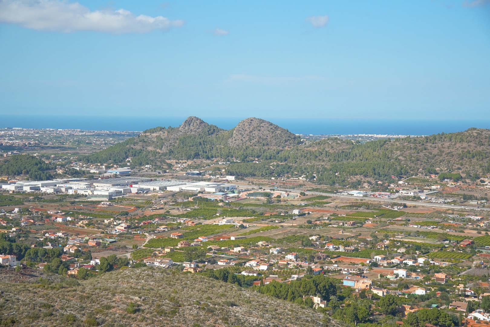 Panoramisch uitzicht vanaf het pand over de Pedreguer-vallei, met de omliggende bergen en de Middellandse Zee aan de horizon onder een heldere hemel.
