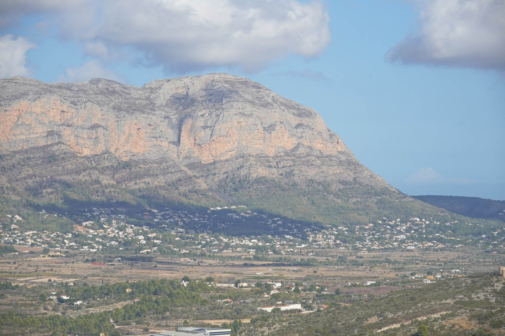 Panoramisch uitzicht vanaf het pand over de vallei en het kalksteengebergte, waarbij de integratie van woonwijken in het mediterrane landschap zichtbaar is.