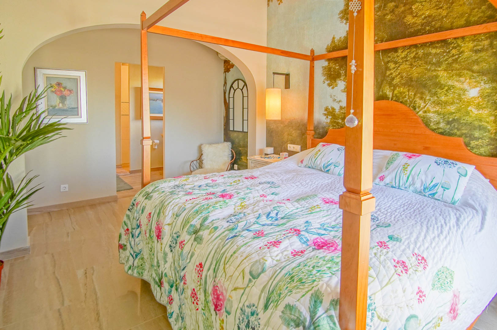 Hoofdslaapkamer met houten hemelbed, landschapsmuurschildering en gepolijste marmeren vloer. Een boogdoorgang biedt directe toegang tot de en-suite badkamer.