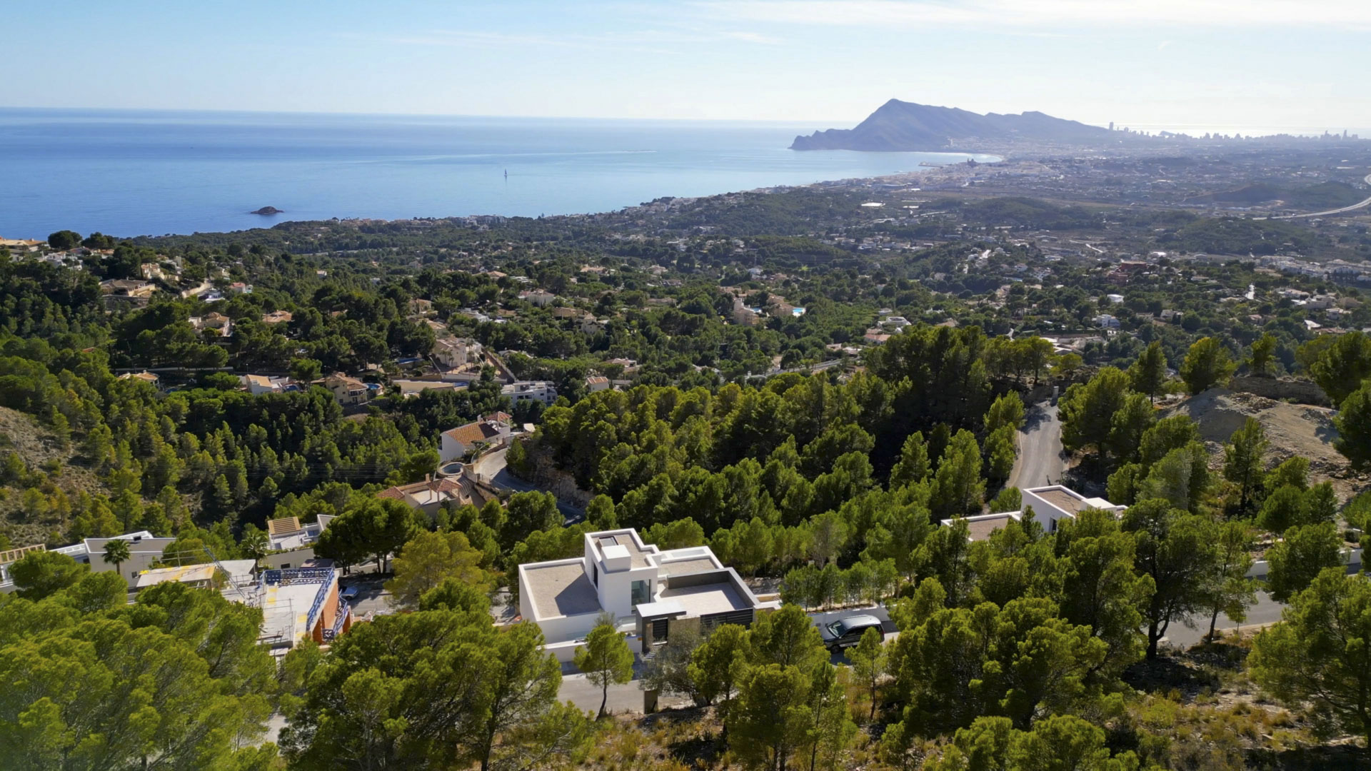 Luchtfoto van de moderne villa in Sierra de Altea, gelegen in een dennenbos met panoramisch uitzicht op de Middellandse Zee en de kustlijn.