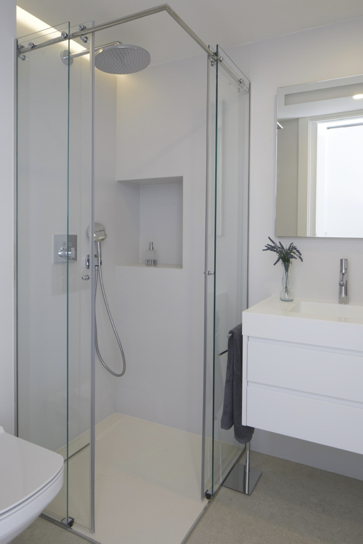 Moderne badkamer met glazen inloopdouche, regendouchekop en ingebouwde nis. Voorzien van een zwevend wit wastafelmeubel met chromen kranen en een strakke afwerking.