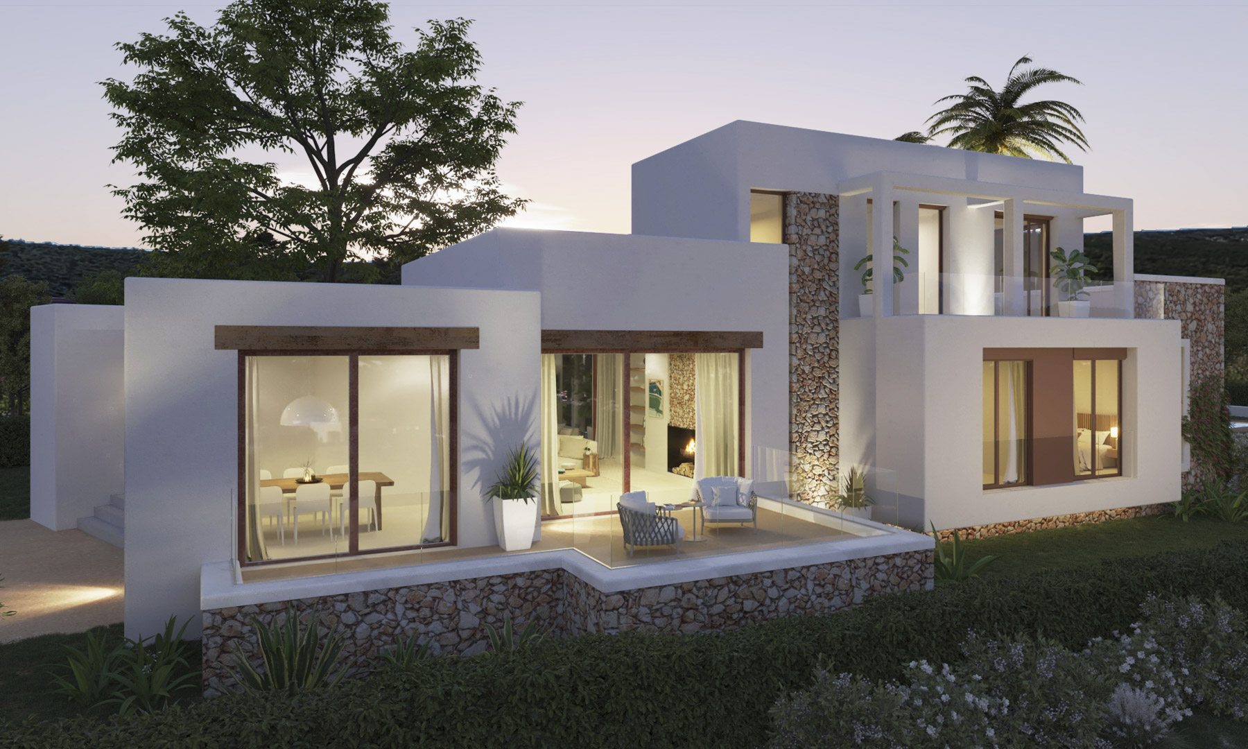Gevel in Ibiza-stijl met natuurstenen muren en witte wanden. Het verhoogde terras met glazen balustrades biedt zicht op de verlichte leefruimtes en de omliggende tuin.