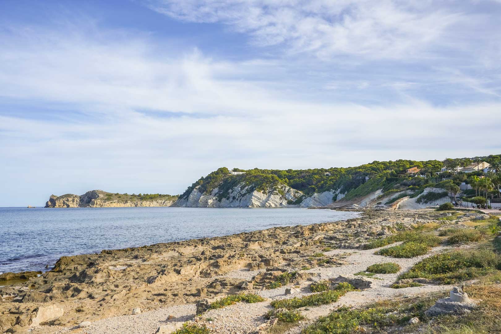 Panoramisch uitzicht op de rotsachtige kustlijn van Jávea, met kalkstenen kliffen en de mediterrane kust onder een heldere hemel.