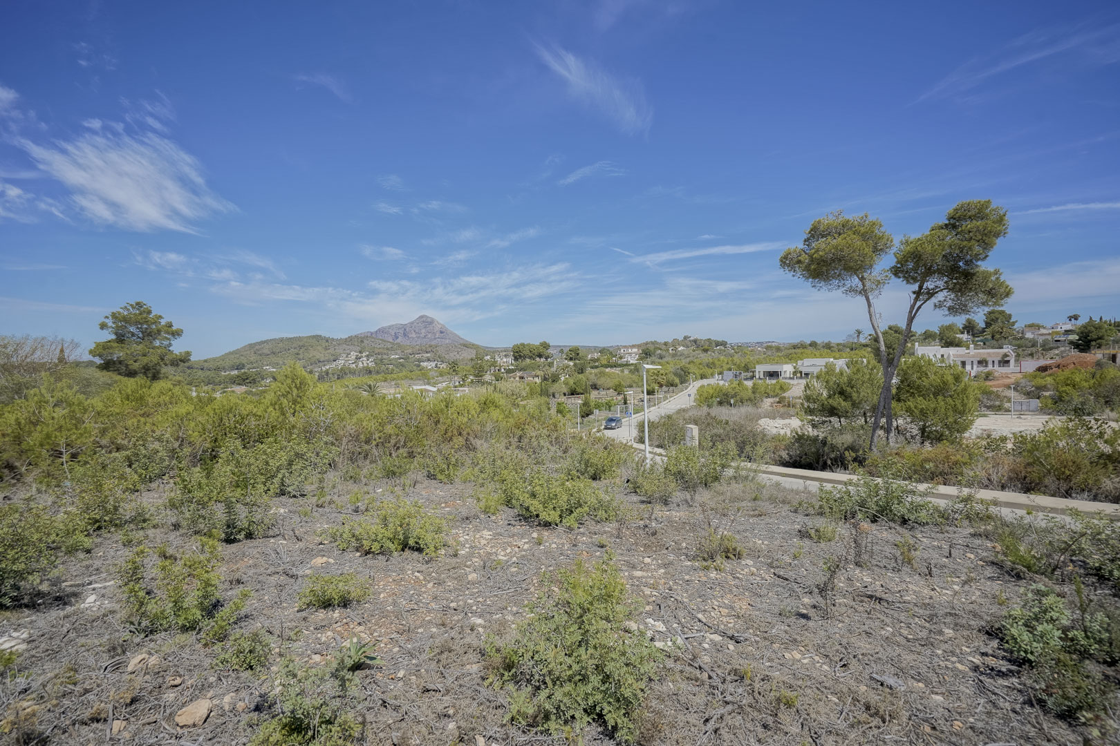 Panoramisch uitzicht vanaf het perceel op de Montgó-berg, omgeven door mediterrane vegetatie en een helderblauwe lucht in de wijk Valsol.