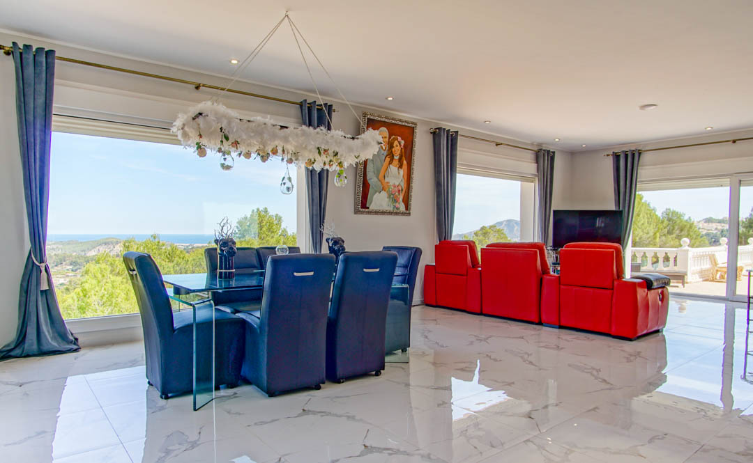 Open woon- en eetkamer met gepolijste marmeren vloeren, modern meubilair en grote raampartijen met panoramisch uitzicht op de Middellandse Zee.