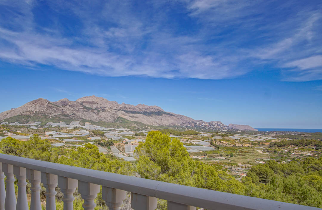 Panoramisch uitzicht vanaf het terras met witte balustrade over de vallei, de omliggende bergen en de horizon van de Middellandse Zee.