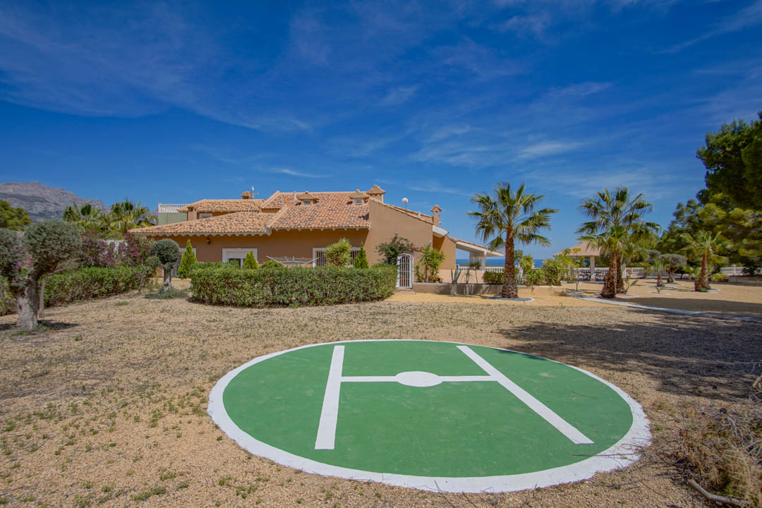 Privé-helikopterplatform gelegen op het uitgestrekte perceel, omgeven door mediterrane tuinen met palmbomen en uitzicht op de traditionele architectuur van de villa.