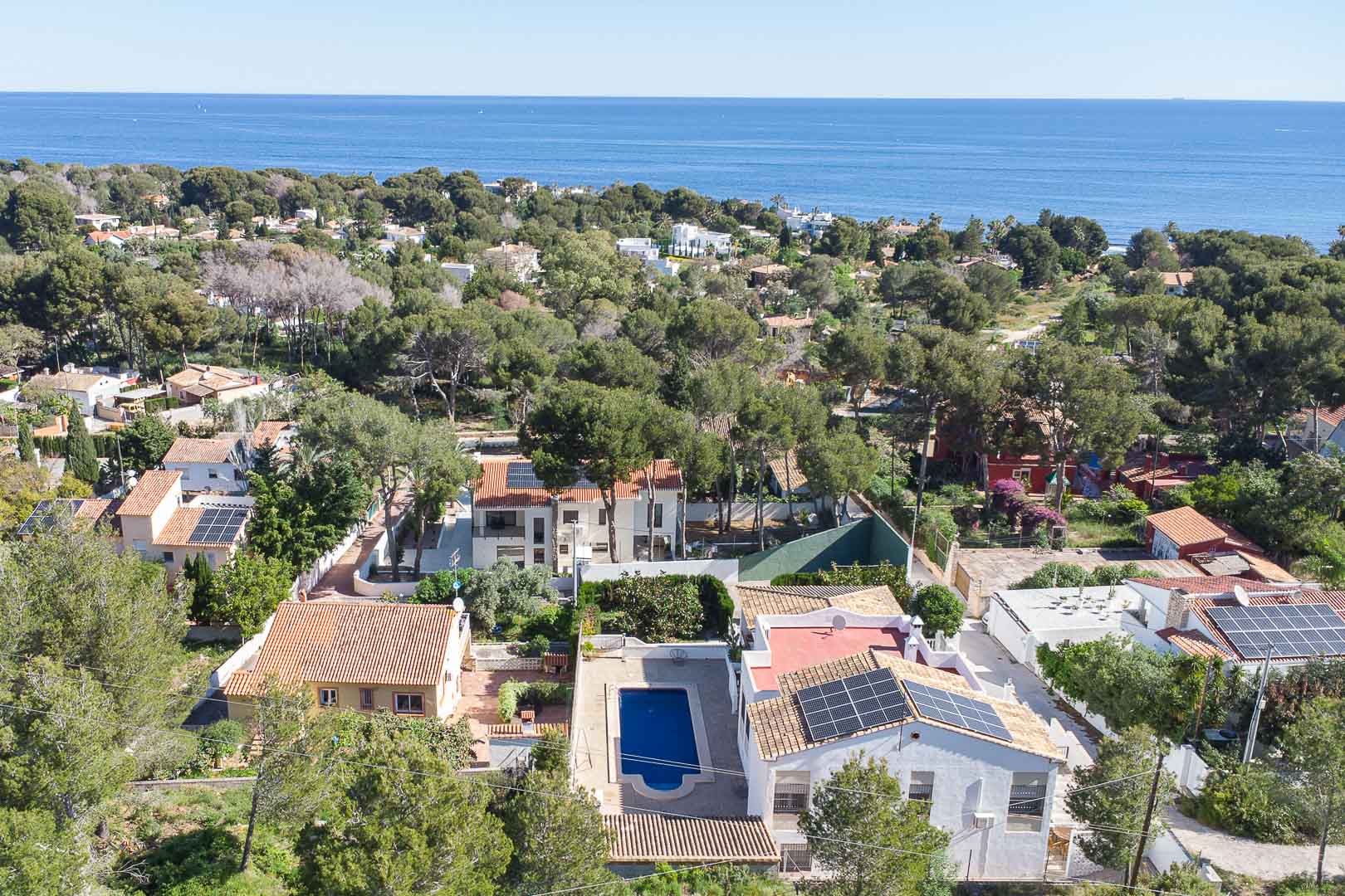 Luchtfoto van de villa in Las Rotas, met privézwembad, zonnepanelen en een bosrijke mediterrane omgeving met uitzicht op zee.