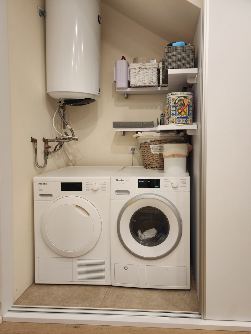 Wasruimte uitgerust met Miele wasmachine en droger, een zonneboiler en handige opbergschappen in een efficiënte indeling.