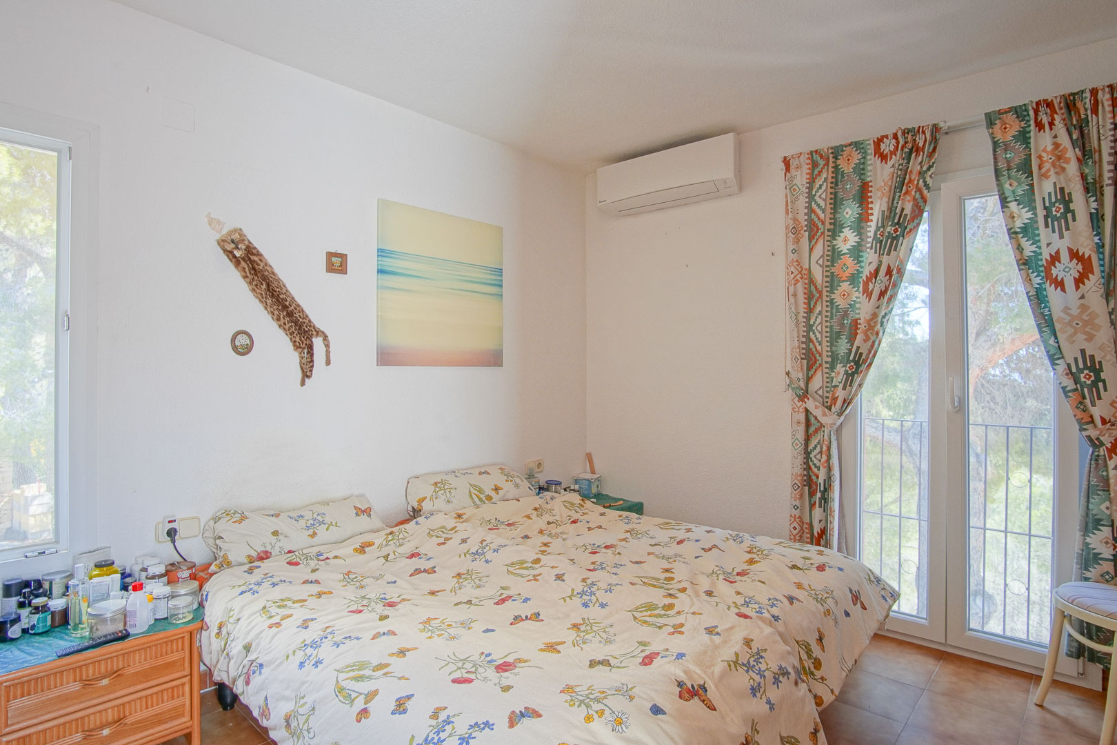 Lichtrijke slaapkamer voorzien van airconditioning, directe toegang tot het terras via een glazen deur en een rustieke tegelvloer.