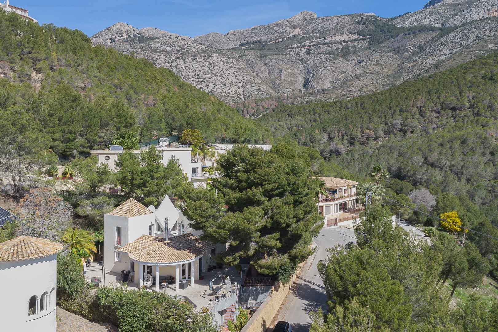 Luchtfoto van de villa met mediterrane architectuur en pannendaken, gelegen in een bosrijke omgeving aan de voet van het indrukwekkende gebergte.