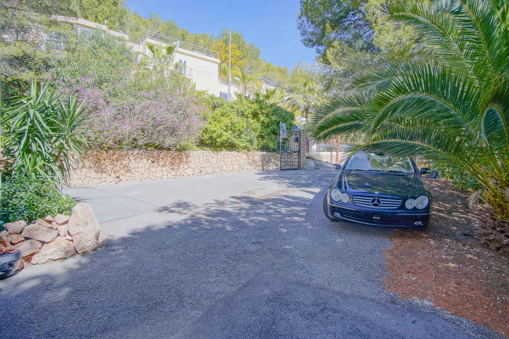Ruime geplaveide parkeergelegenheid buiten, omgeven door natuurstenen muren en volwassen mediterrane beplanting voor optimale privacy.