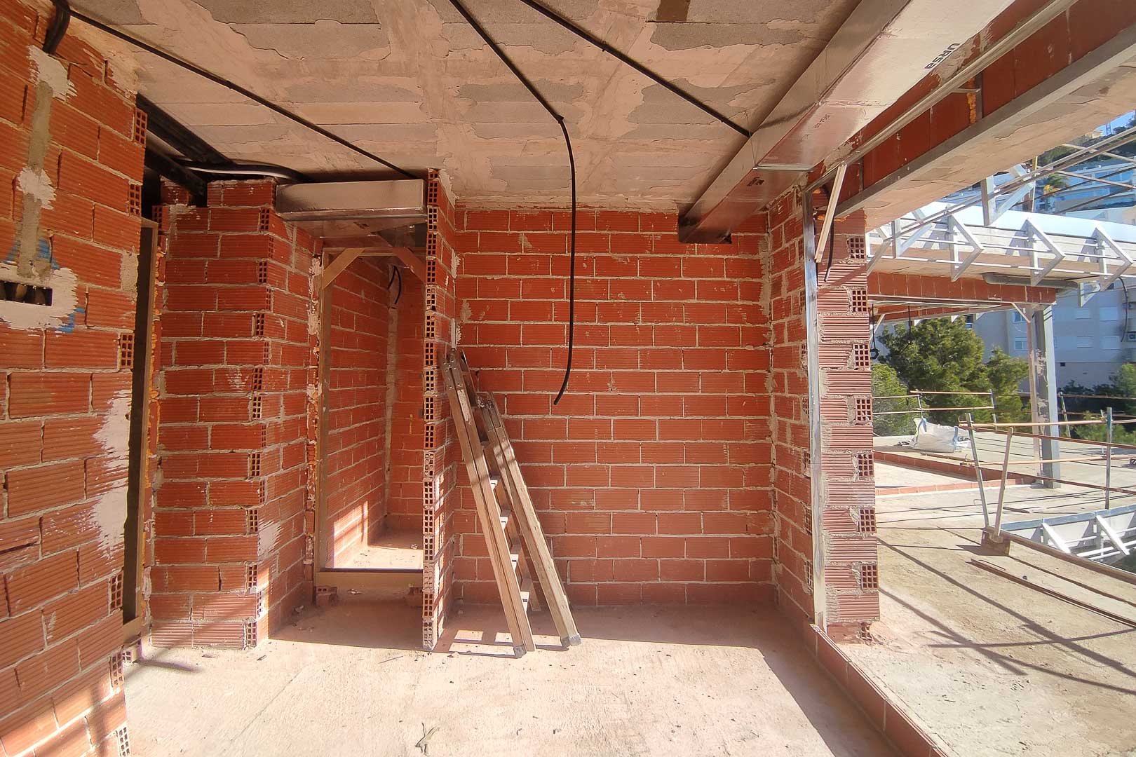 Bouwfase van de villa met bakstenen muren, betonnen plafonds en de installatie van airconditioningkanalen en elektrische bedrading.