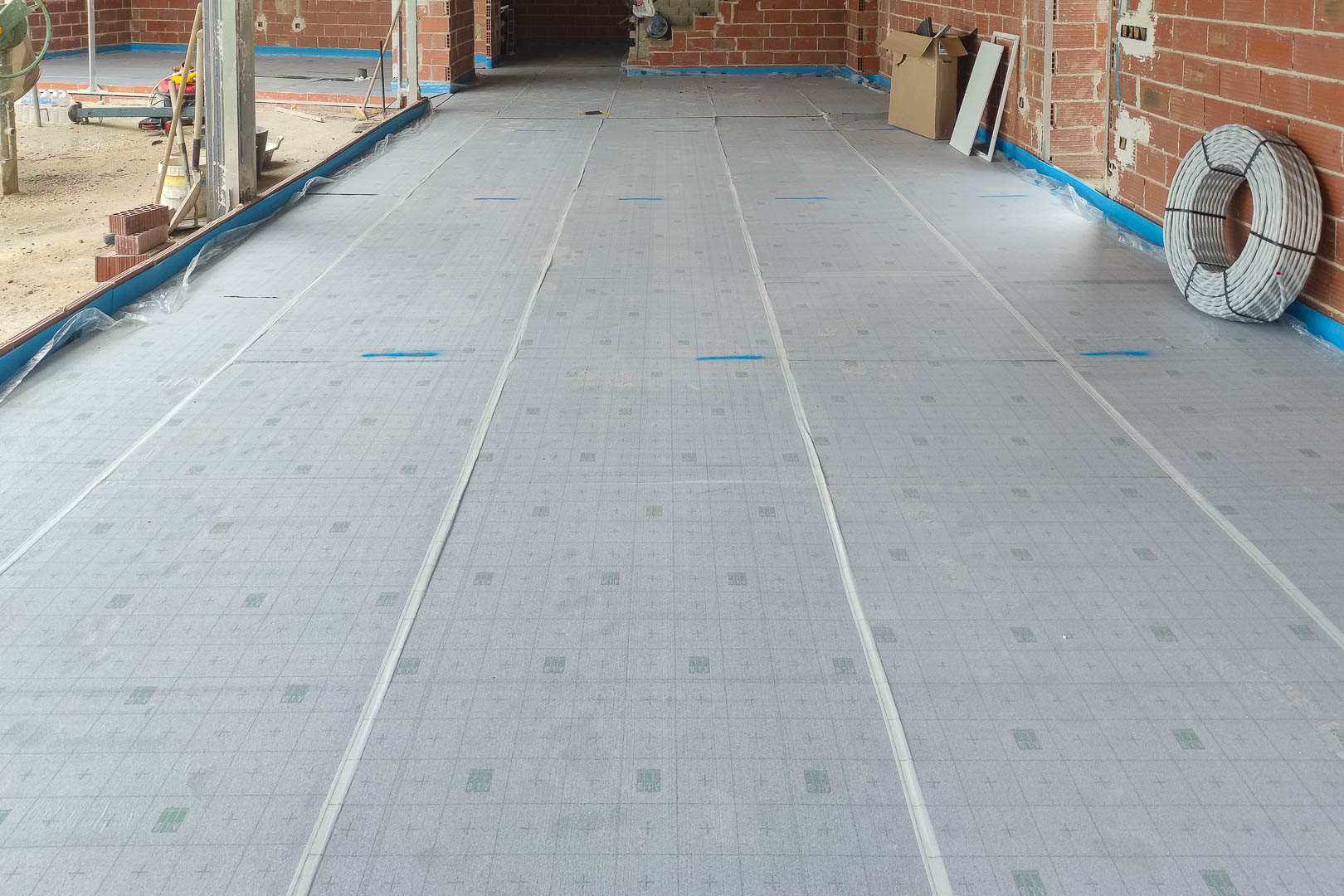 Installatie van thermische isolatiepanelen voor de vloerverwarming, met focus op de technische voorbereiding en hoogwaardige materialen in de ruwbouwfase.