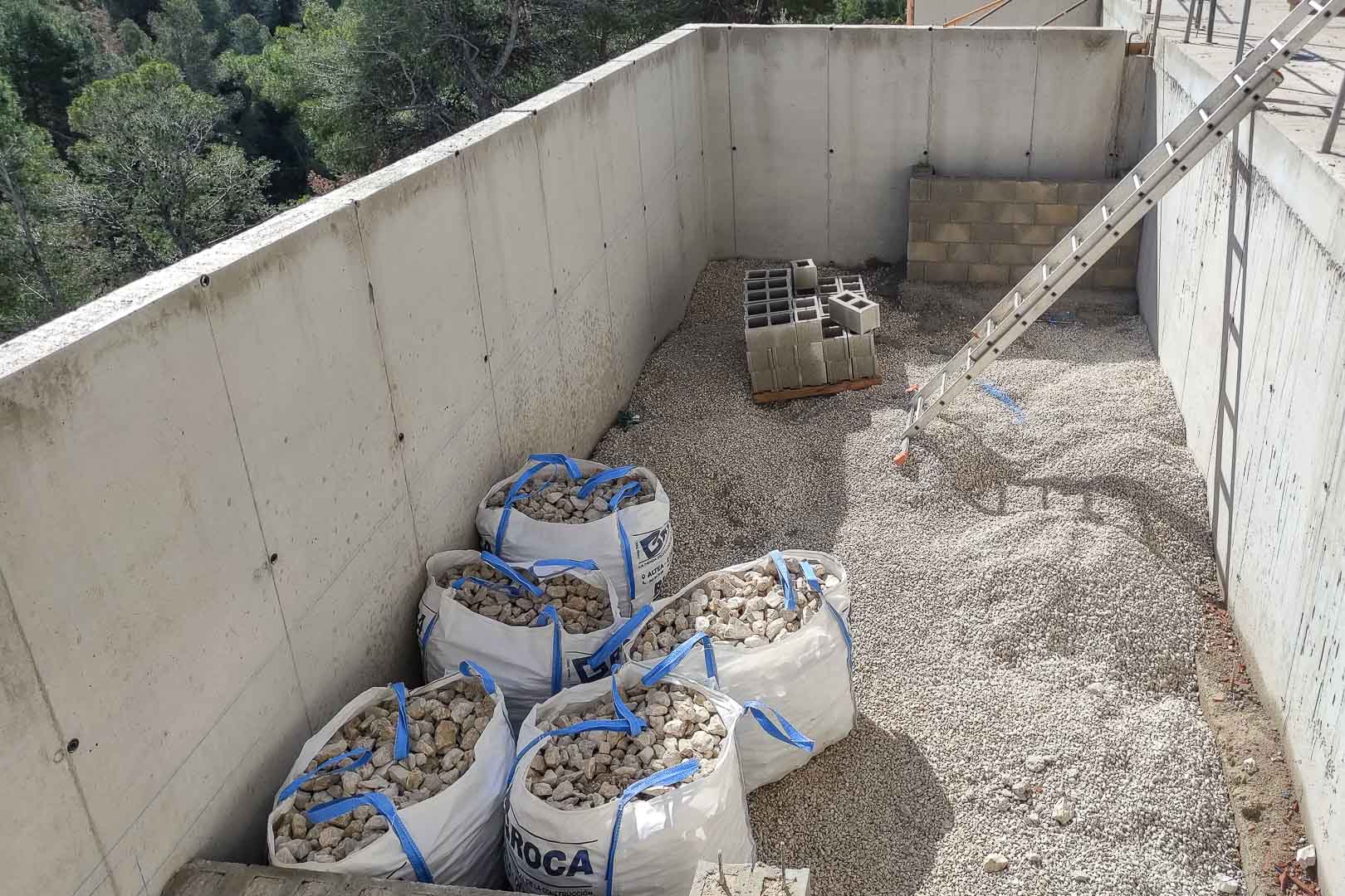 Voortgang van de bouw met gewapend betonnen muren, funderingsgrind en bouwmaterialen te midden van het mediterrane landschap van Altea.
