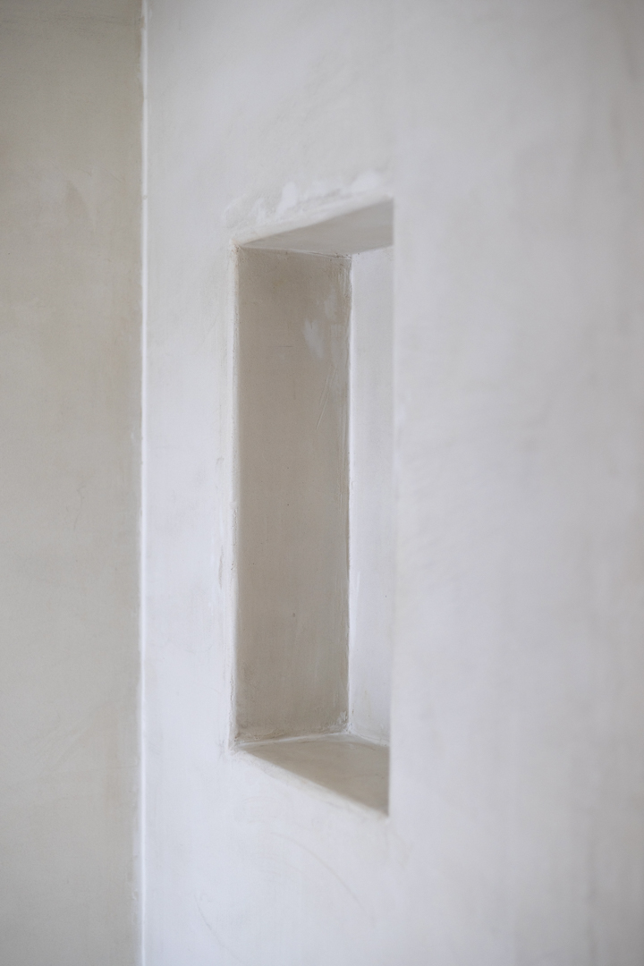 Detail van een rechthoekige nis in een gladde witte muur. Natuurlijke verlichting.
