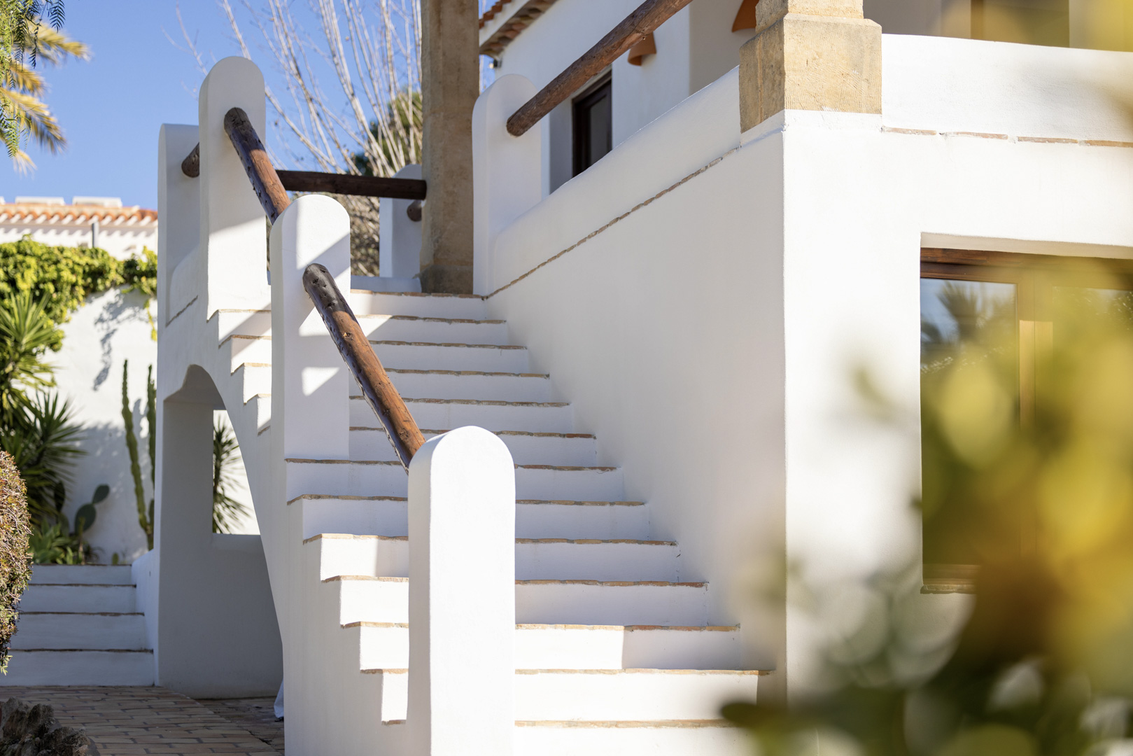 Detail van witte buitentrap met houten leuning bij villa in Jávea. Helder mediterraan design.