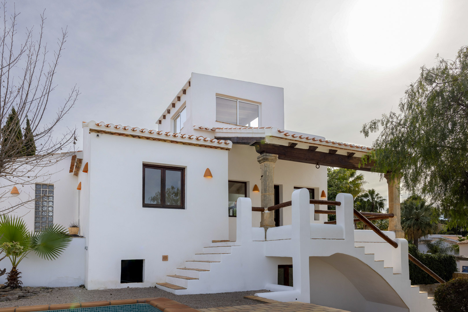 Exterieur van de villa met de hoofdingang met toegangstrap en mediterrane architectonische details.