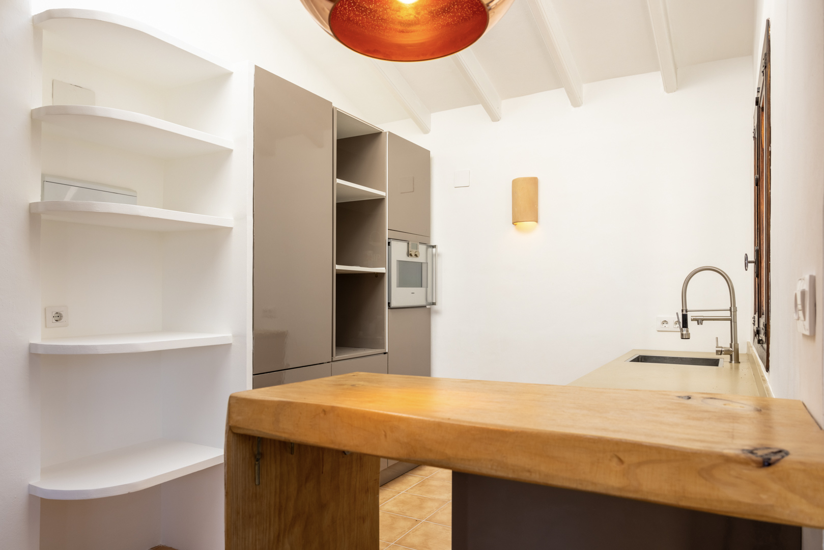 Keukendetail met houten eiland, witte schappen en warme verlichting.