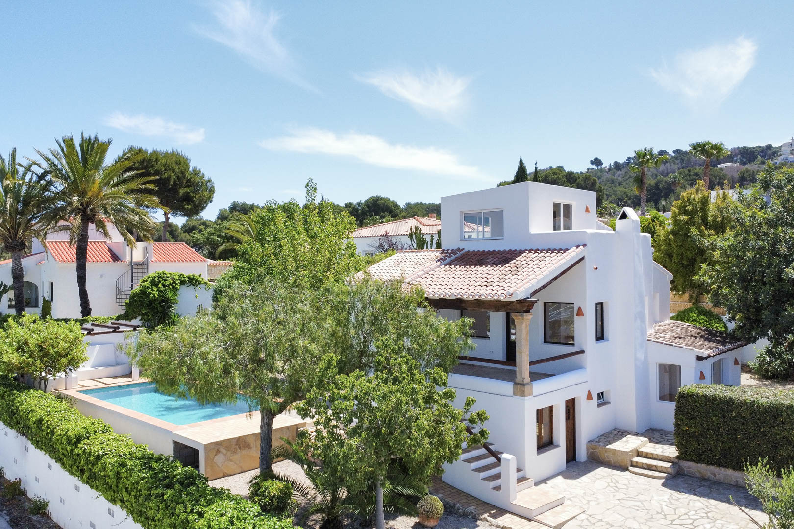 Verhoogd uitzicht op de witte villa met zwembad, tuin en rode dakpannen in Jávea.