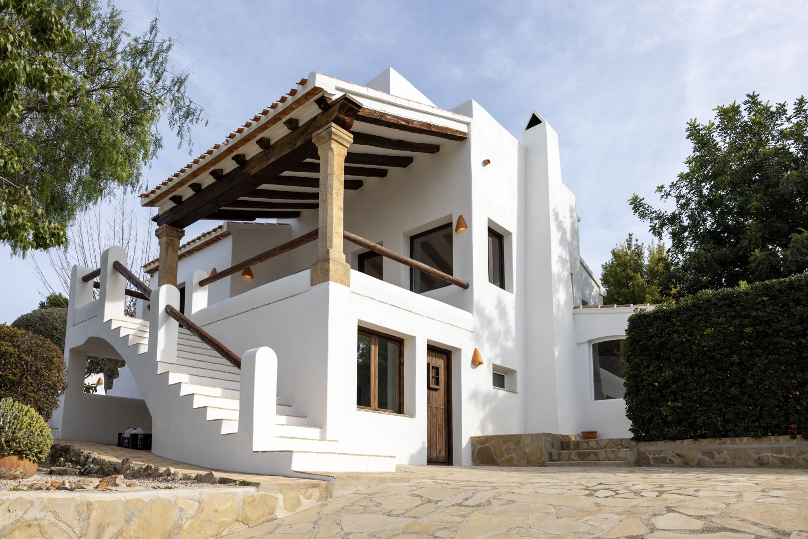 Villafassade in Jávea met overdekt terras, stenen zuilen en toegang via buitentrap.