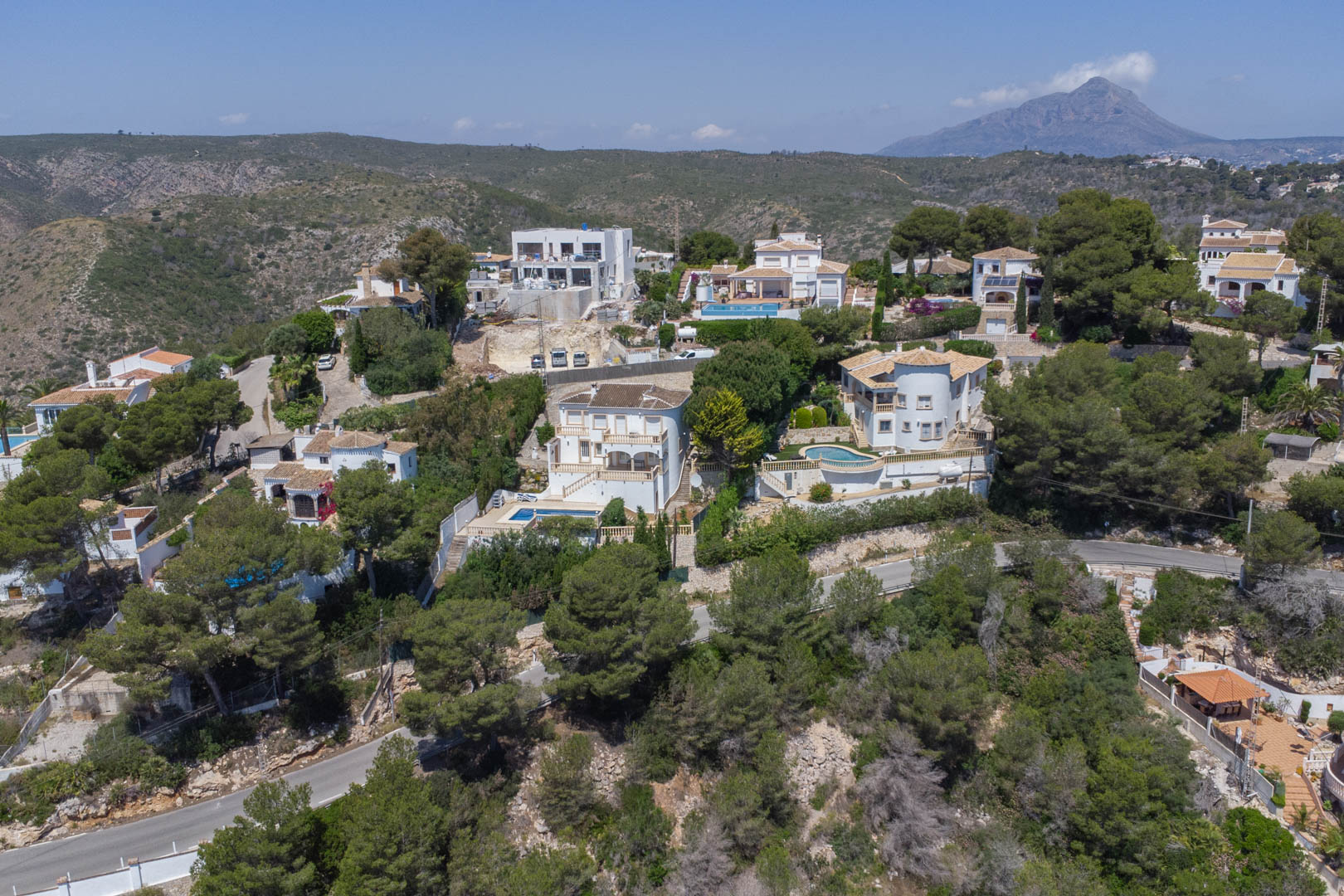 Luchtfoto van de woonwijk Costa Nova in Jávea, met mediterrane villa's tussen de pijnbomen en de berg Montgó aan de horizon.