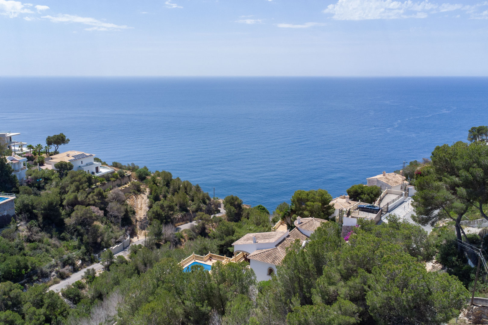Verhoogd panoramisch uitzicht op de Middellandse Zee vanuit Costa Nova, met dichte dennenbossen en kustvilla's nabij de kust van Jávea.